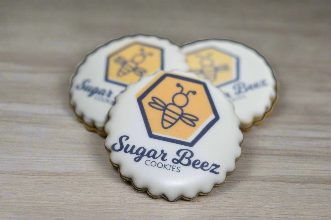 Round scalloped cookie with Sugar Beez logo printed on white icing.
