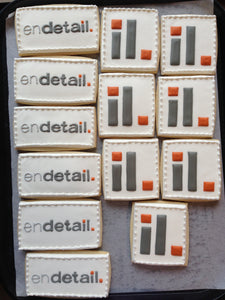 Rectangle and Square sugar cookies with Endetail logo in 2 designs in gray and orange icing on white icing background.